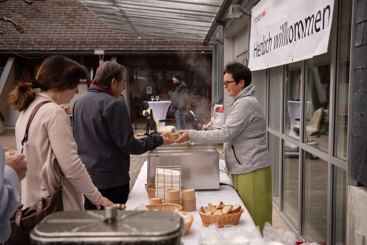 Draussen wurde warme Suppe serviert. Man sieht, wie Suppe geschöpft und ausgeteilt wird.